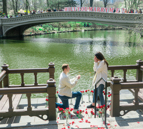 A man proposing to a woman by a water bridge